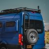 Blue Sprinter van outfitted with Owl Vans rear tire carrier paired with Rugged design concepts sprinter rear bumper and RX4 and Baja lp roof rack